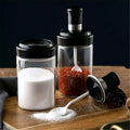 Transparent glass jar with built-in spoon for easy kitchen access to spices