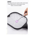 A hand uses a metal probe to demonstrate the purple light of the electric grid on a black mosquito killer racket.