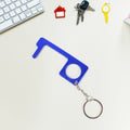 Hand holding Safe Touch Tool metal keychain used for hygienic door opening