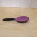 Person brushing hair with cushioned paddle brush for smooth styling