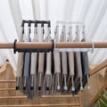 Organivo space-saving hanger with adjustable arms, demonstrating ease of use for trousers.